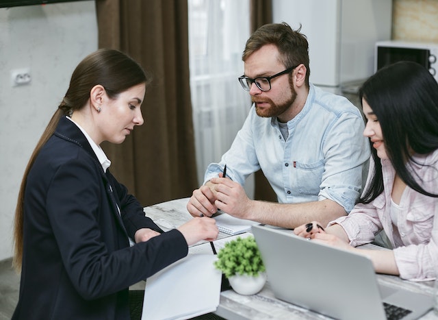 Loan provider discussing a loan with a couple at a desk